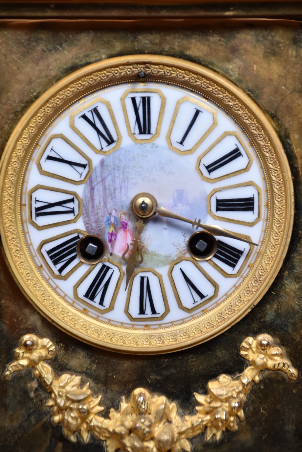 A three-piece antique French gilt metal and painted porcelain clock garniture set with matching side urns, each housed under a glass dome on a black base. View XXI