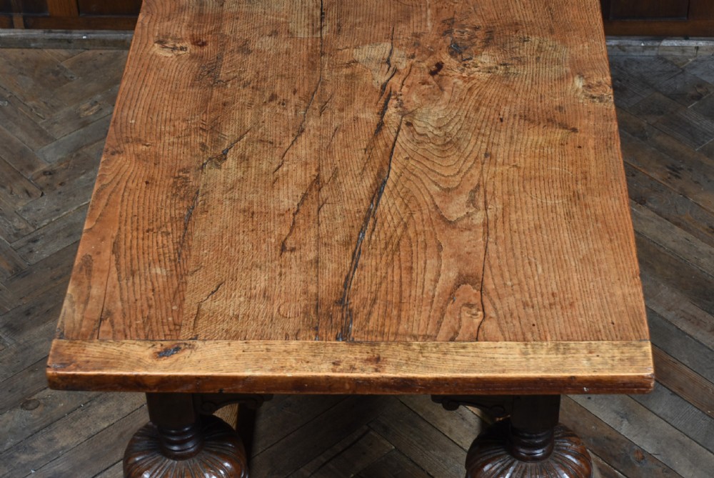An 18th-century solid oak refectory table featuring a plank top and carved bulbous cup-and-cover turned legs resting on a stretcher base. View III