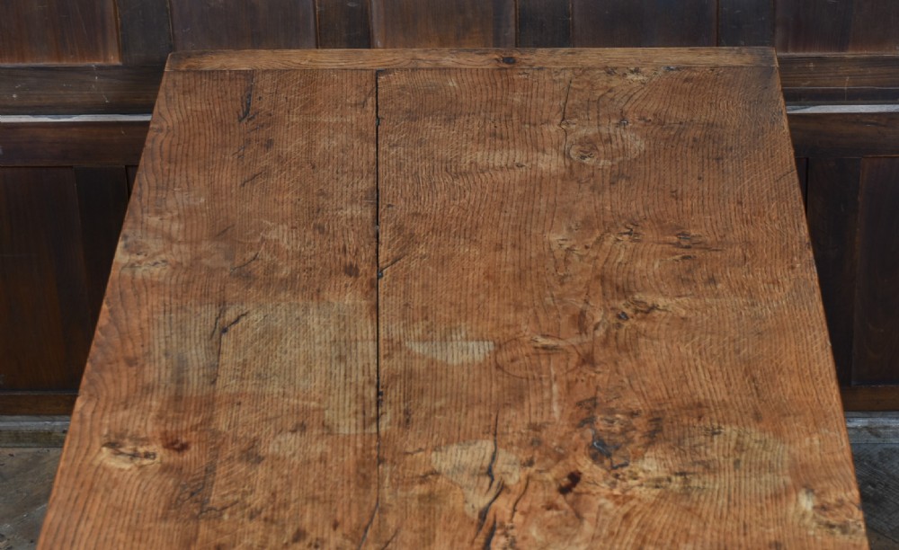 An 18th-century solid oak refectory table featuring a plank top and carved bulbous cup-and-cover turned legs resting on a stretcher base. View V