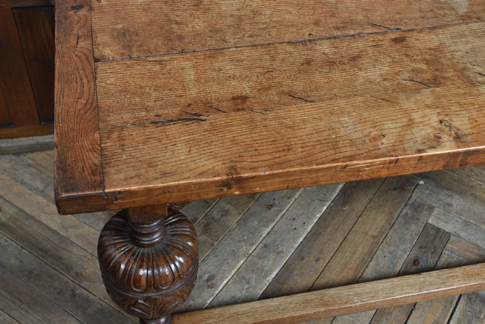 An 18th-century solid oak refectory table featuring a plank top and carved bulbous cup-and-cover turned legs resting on a stretcher base. View X