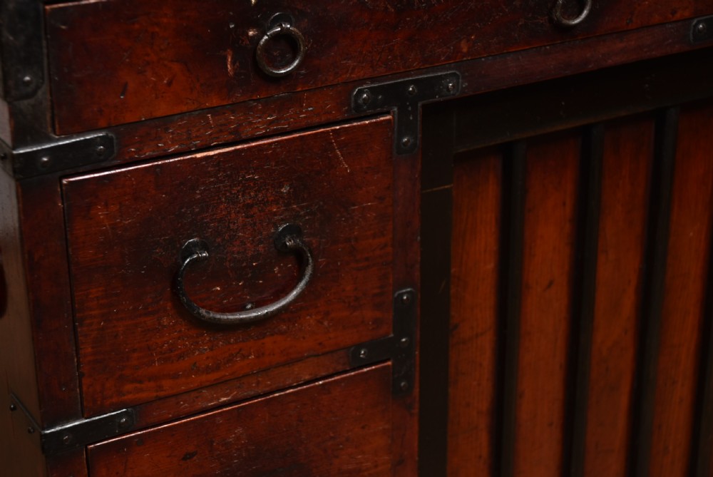 A Japanese Choba Tansu merchant chest featuring dark reddish-brown wood, sliding slatted doors, multiple small drawers, and black iron hardware. View II