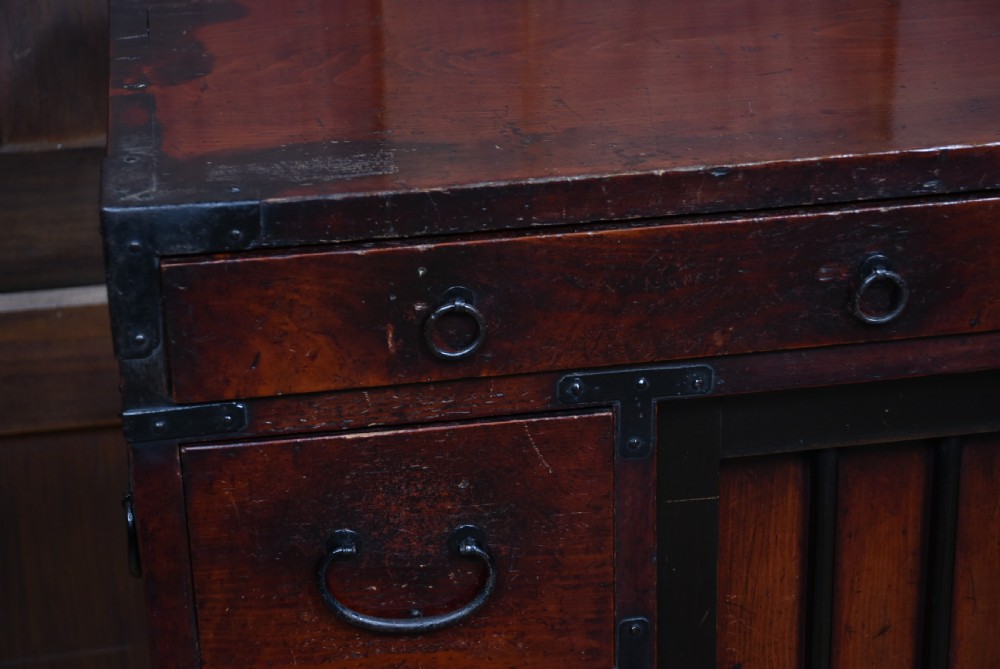 A Japanese Choba Tansu merchant chest featuring dark reddish-brown wood, sliding slatted doors, multiple small drawers, and black iron hardware. View III