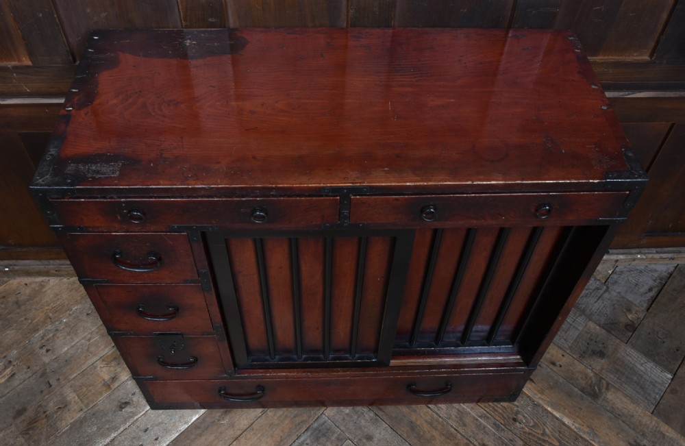 A Japanese Choba Tansu merchant chest featuring dark reddish-brown wood, sliding slatted doors, multiple small drawers, and black iron hardware. View VII
