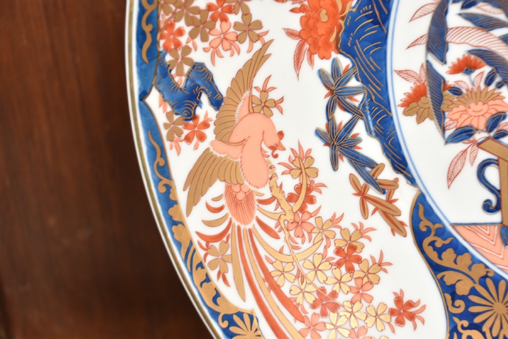 A large round Japanese Imari porcelain charger decorated with vibrant cobalt blue, terracotta red, and gilded floral and bird motifs. View VI