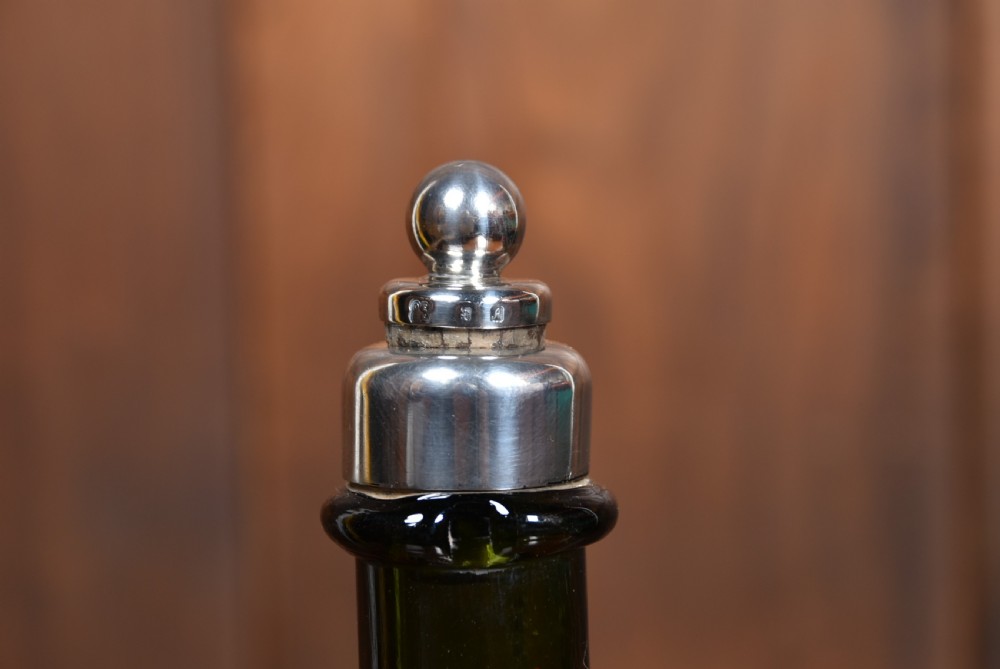 A dark green glass decanter featuring silver collar band, silver ball stopper, and a silver oval plaque engraved with WHISKEY. View VII