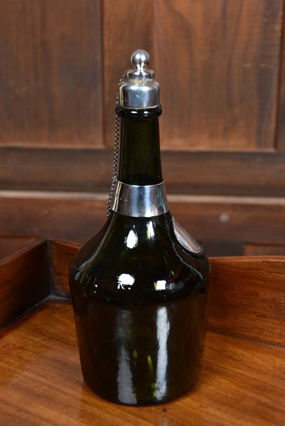 A dark green glass decanter featuring silver collar band, silver ball stopper, and a silver oval plaque engraved with WHISKEY. View VIII