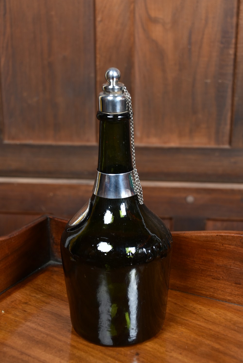 A dark green glass decanter featuring silver collar band, silver ball stopper, and a silver oval plaque engraved with WHISKEY. View X