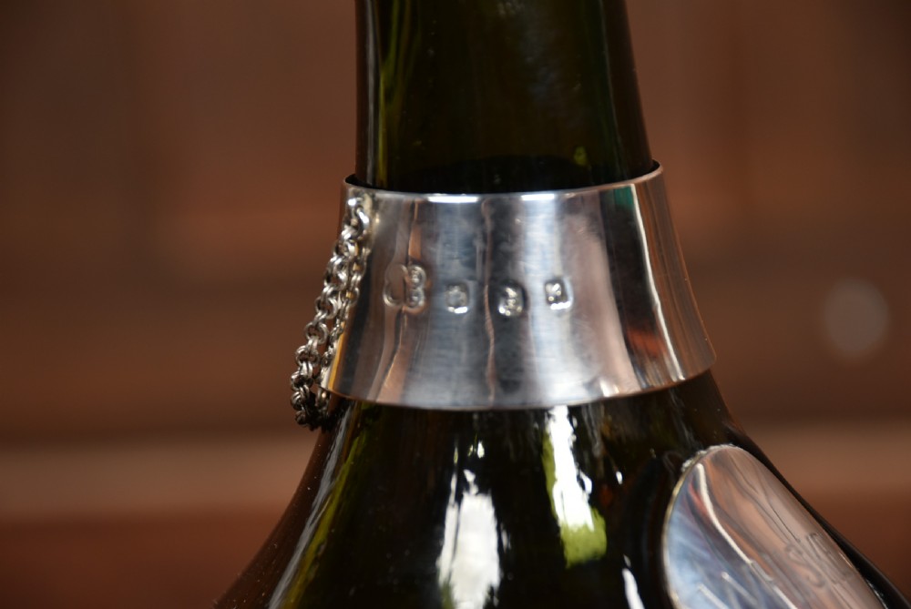 A dark green glass decanter featuring silver collar band, silver ball stopper, and a silver oval plaque engraved with WHISKEY. View XII