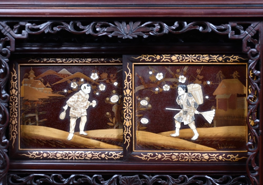 A tall Japanese Meiji period dark hardwood shodana cabinet featuring asymmetrical shelving, mother-of-pearl inlaid panels, bird carvings, and a cresting pediment. View III