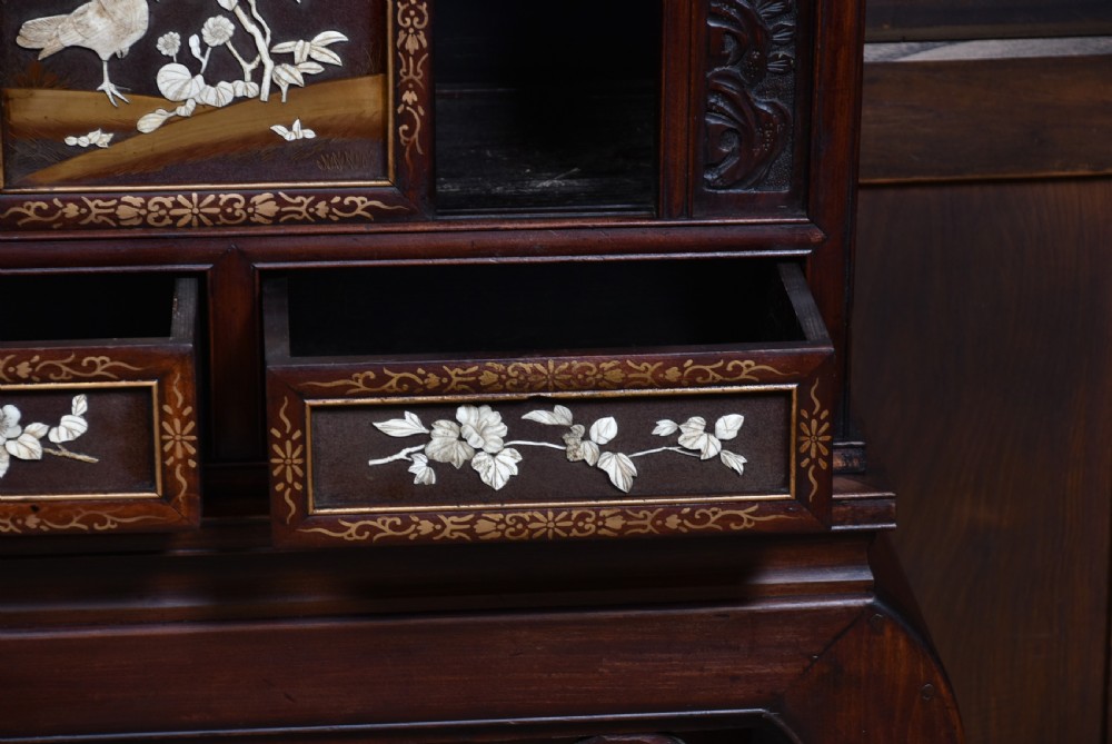 A tall Japanese Meiji period dark hardwood shodana cabinet featuring asymmetrical shelving, mother-of-pearl inlaid panels, bird carvings, and a cresting pediment. View IX