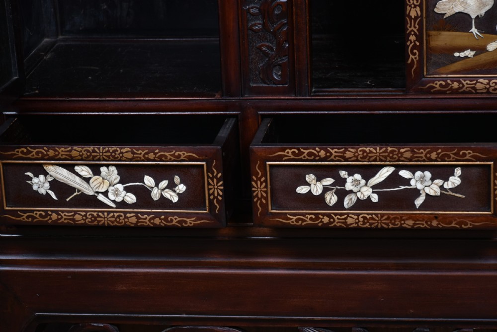 A tall Japanese Meiji period dark hardwood shodana cabinet featuring asymmetrical shelving, mother-of-pearl inlaid panels, bird carvings, and a cresting pediment. View X