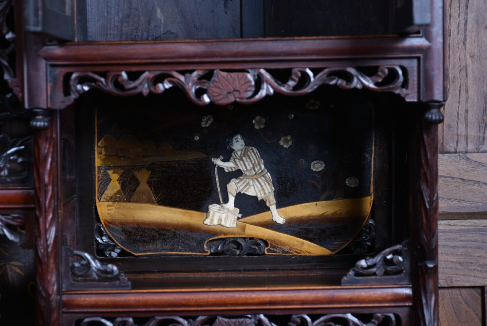 A tall Japanese Meiji period dark hardwood shodana cabinet featuring asymmetrical shelving, mother-of-pearl inlaid panels, bird carvings, and a cresting pediment. View XI