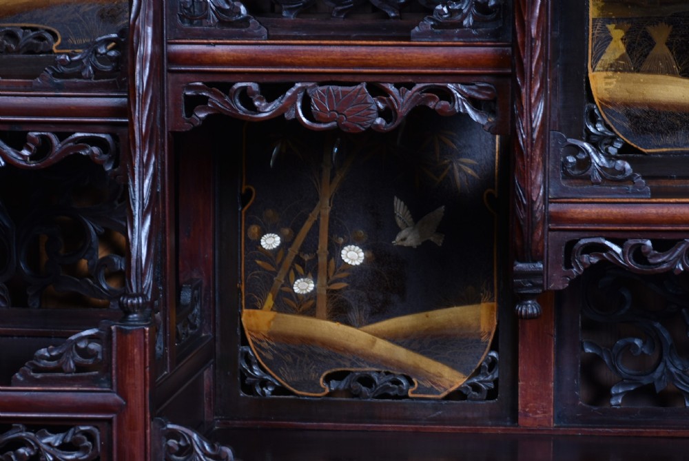 A tall Japanese Meiji period dark hardwood shodana cabinet featuring asymmetrical shelving, mother-of-pearl inlaid panels, bird carvings, and a cresting pediment. View XII