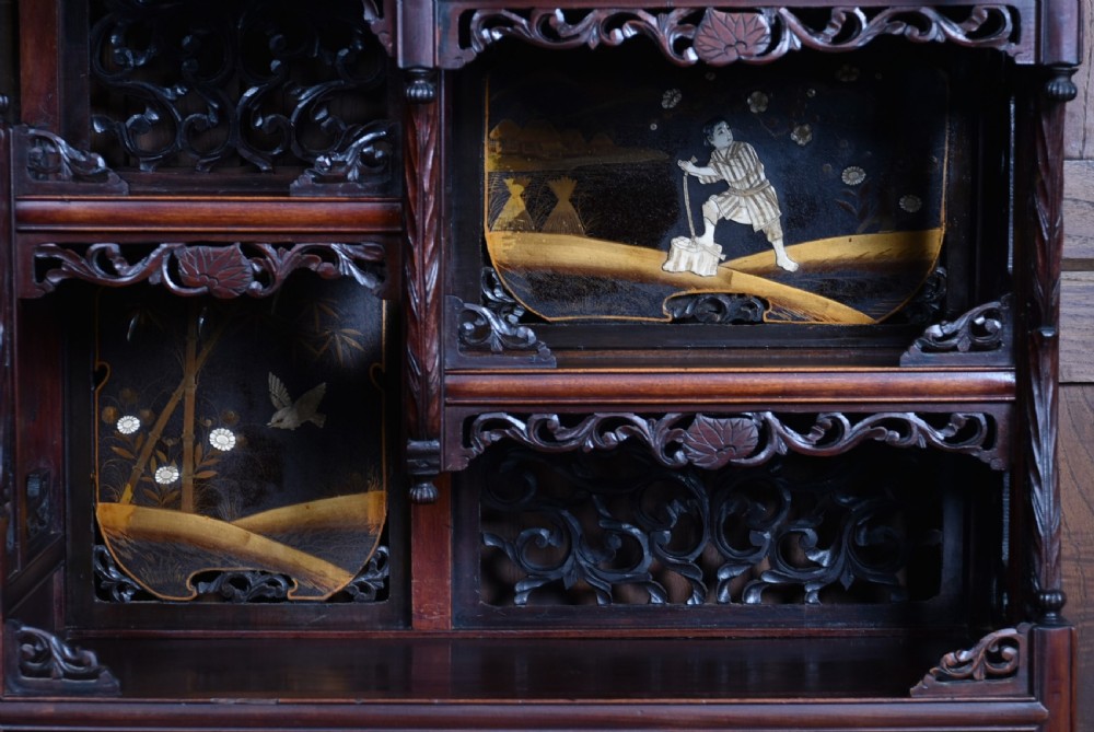 A tall Japanese Meiji period dark hardwood shodana cabinet featuring asymmetrical shelving, mother-of-pearl inlaid panels, bird carvings, and a cresting pediment. View XIV