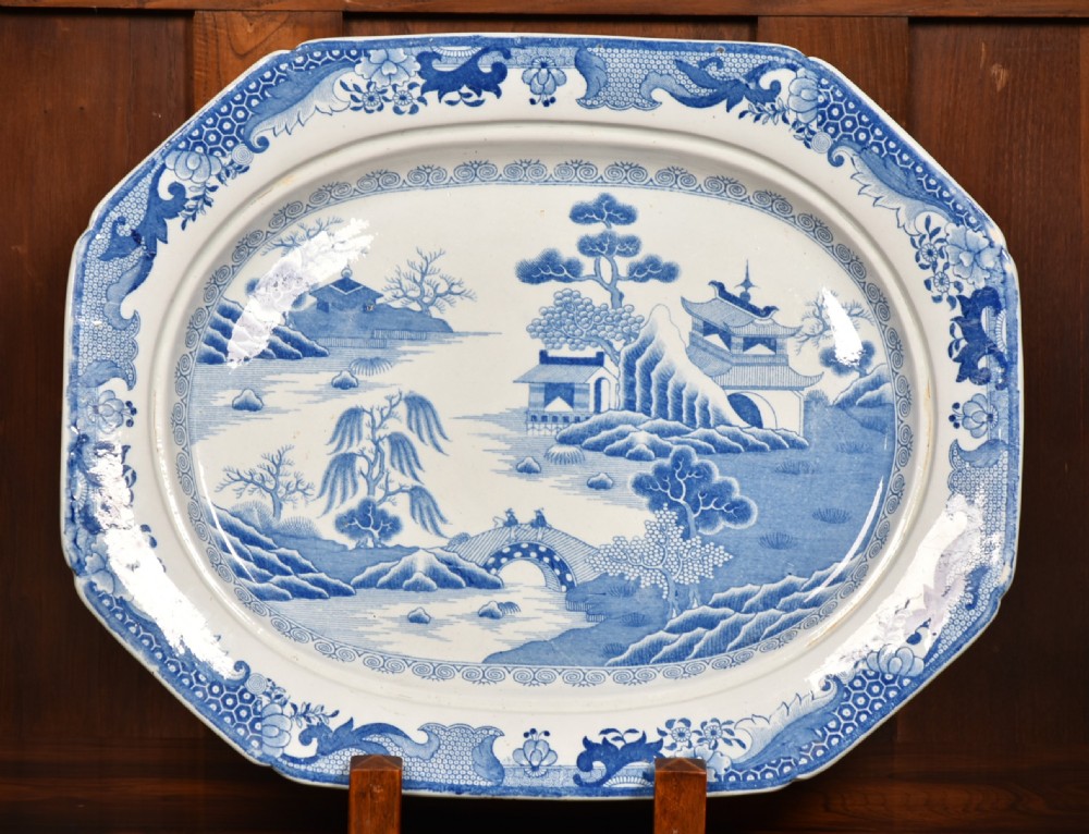 An oval blue and white ironstone charger decorated with an intricate chinoiserie landscape and faceted outer border. View II
