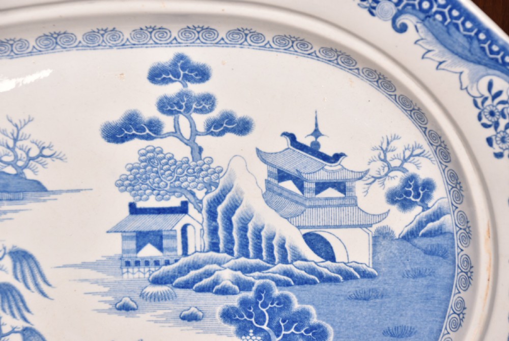 An oval blue and white ironstone charger decorated with an intricate chinoiserie landscape and faceted outer border. View III