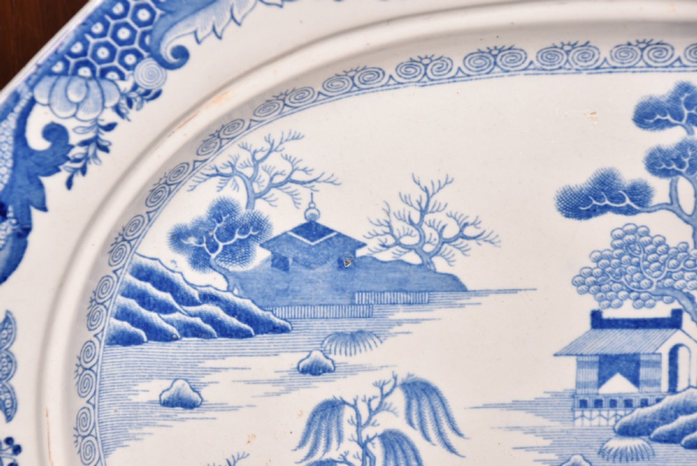 An oval blue and white ironstone charger decorated with an intricate chinoiserie landscape and faceted outer border. View IV