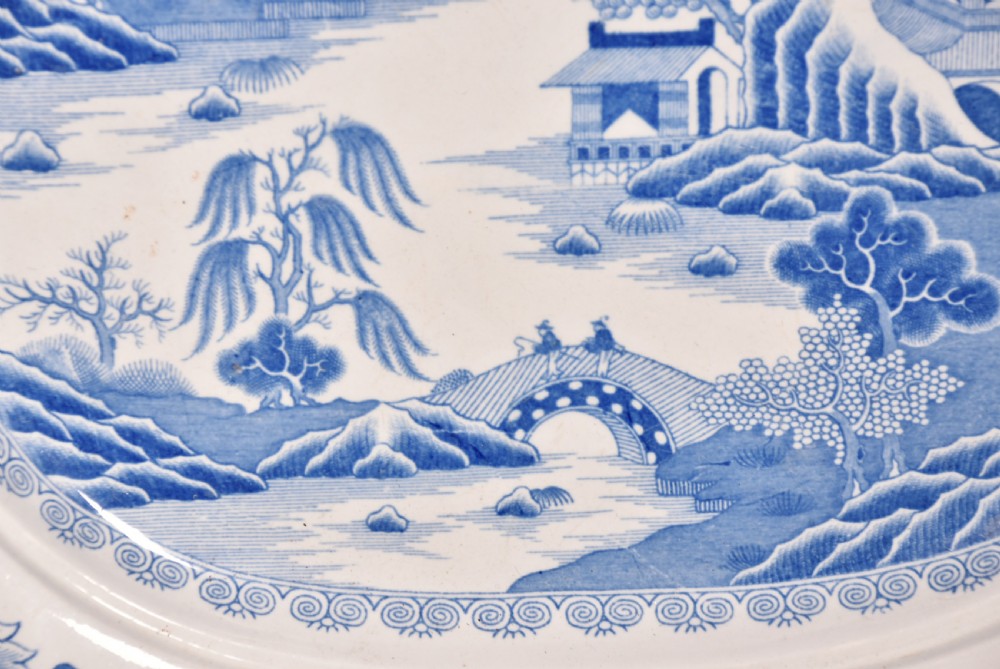 An oval blue and white ironstone charger decorated with an intricate chinoiserie landscape and faceted outer border. View V