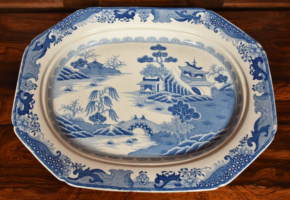 An oval blue and white ironstone charger decorated with an intricate chinoiserie landscape and faceted outer border. View VI