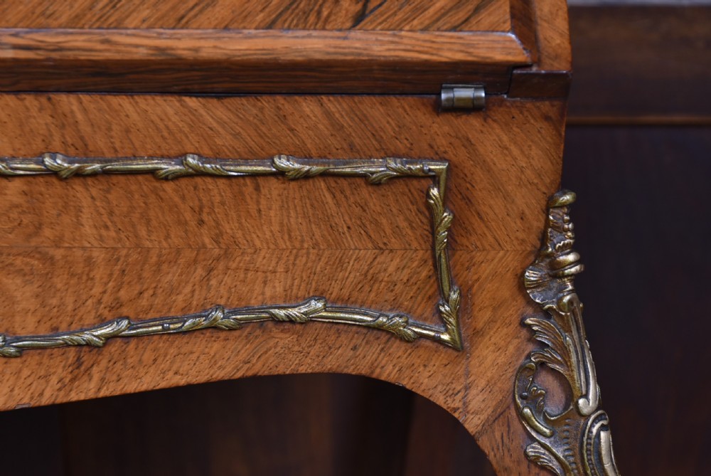 A 19th-century French rosewood bureau de dame featuring slender cabriole legs, brass mounts, a brass gallery top, and a hand-painted scene on the slanted flap front. View VIII