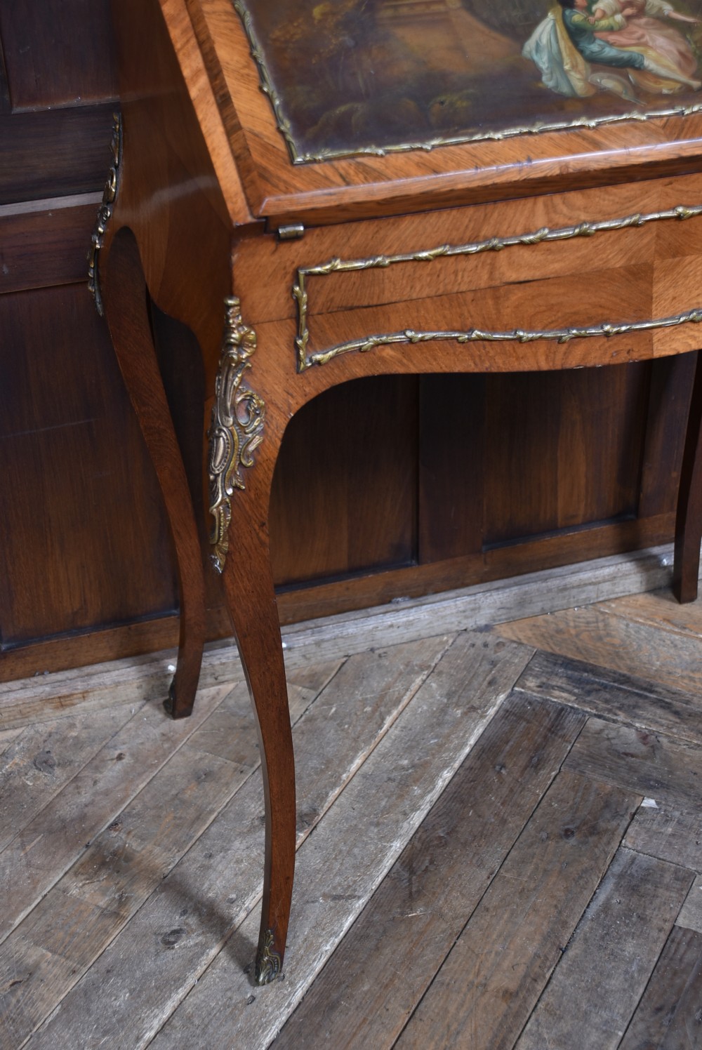 A 19th-century French rosewood bureau de dame featuring slender cabriole legs, brass mounts, a brass gallery top, and a hand-painted scene on the slanted flap front. View IX