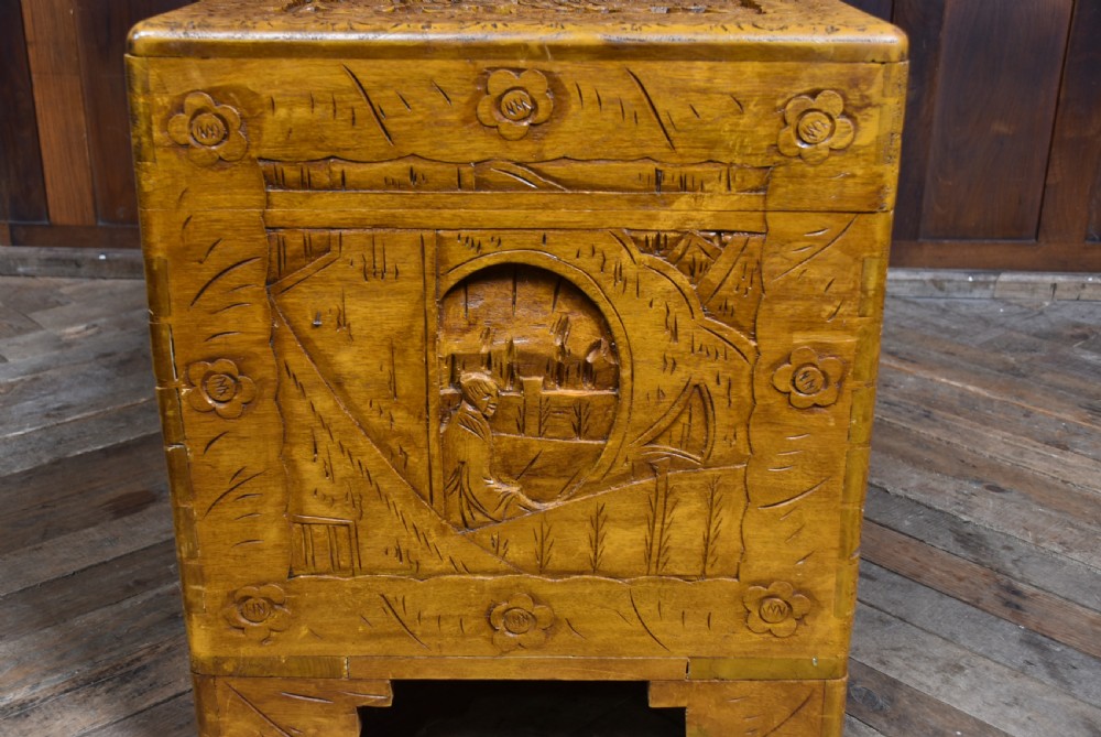 A deeply carved warm brown camphor wood storage chest featuring relief carvings of dragons and birds with a central brass clasp. View XII