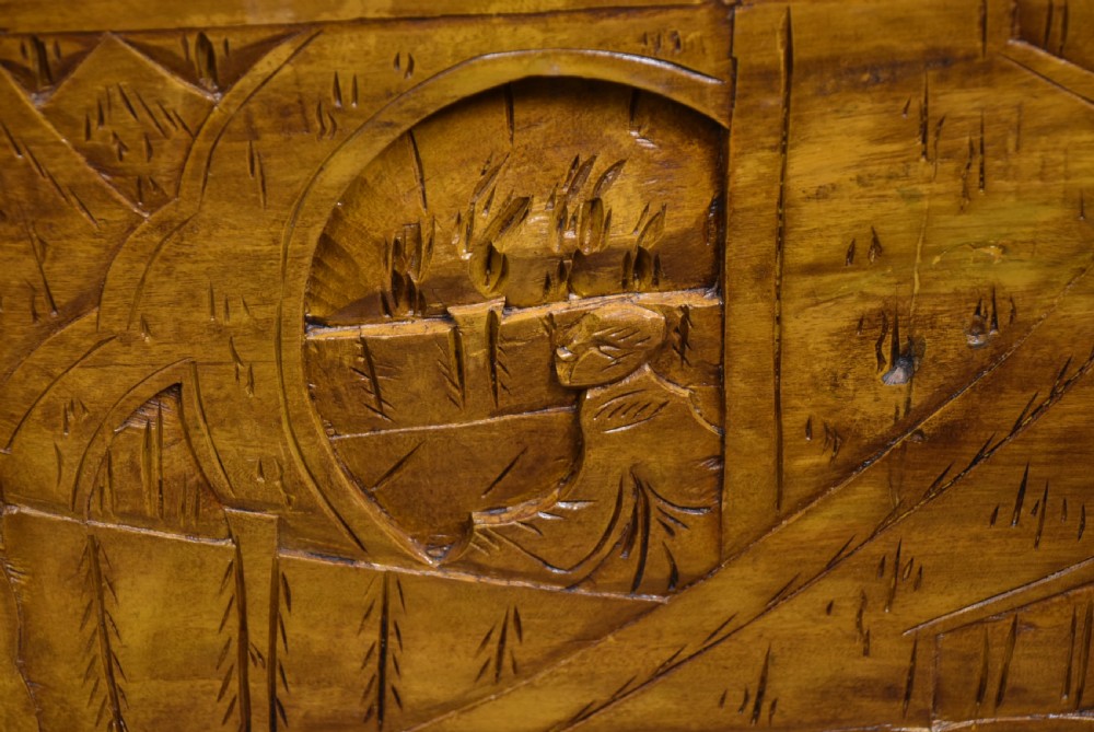 A deeply carved warm brown camphor wood storage chest featuring relief carvings of dragons and birds with a central brass clasp. View XV