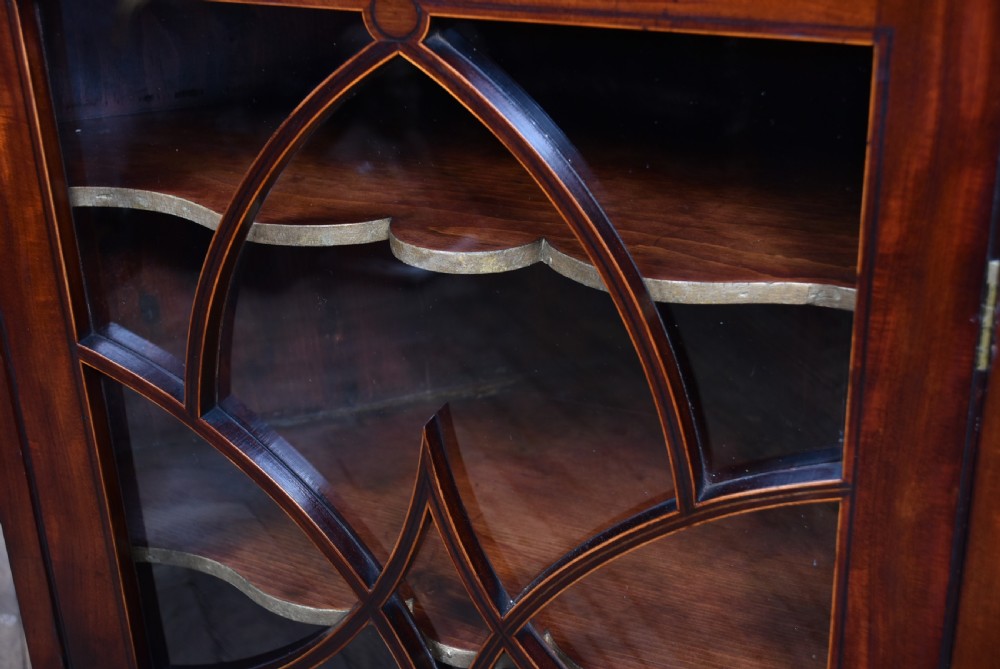 A Georgian mahogany wall-hanging corner cabinet featuring an astragal glazed door with geometric arches and shaped interior shelves. View VI