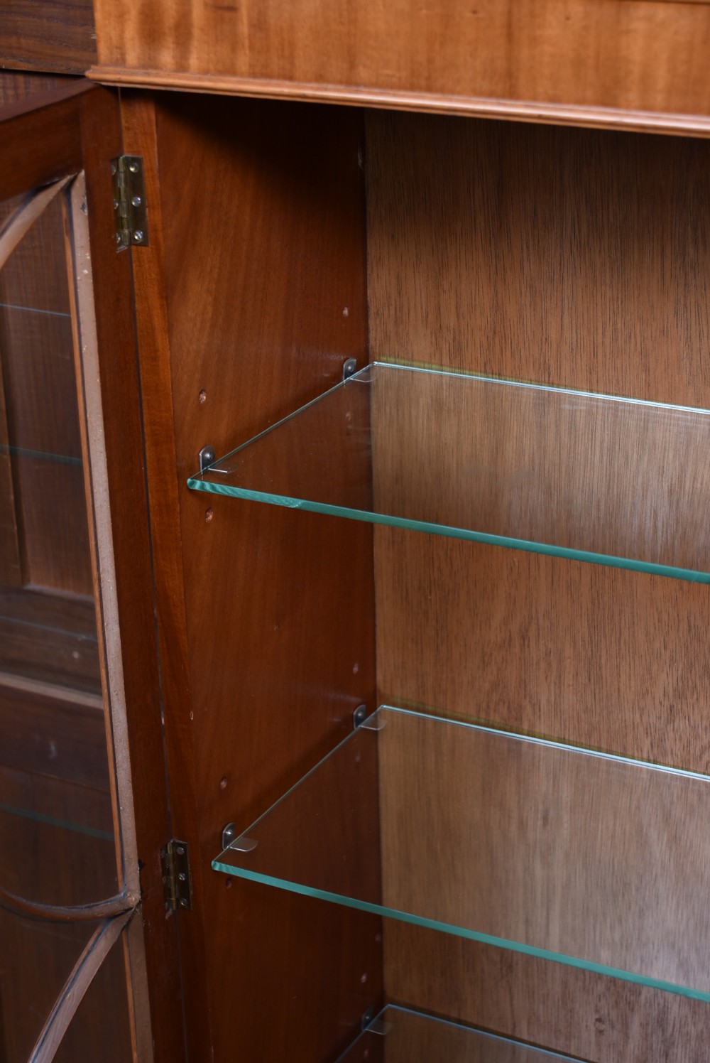 An Edwardian mahogany display cabinet featuring two astragal-glazed doors, glass interior shelving, and splay bracket feet. View V