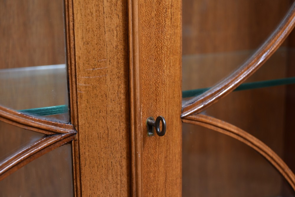 An Edwardian mahogany display cabinet featuring two astragal-glazed doors, glass interior shelving, and splay bracket feet. View VI