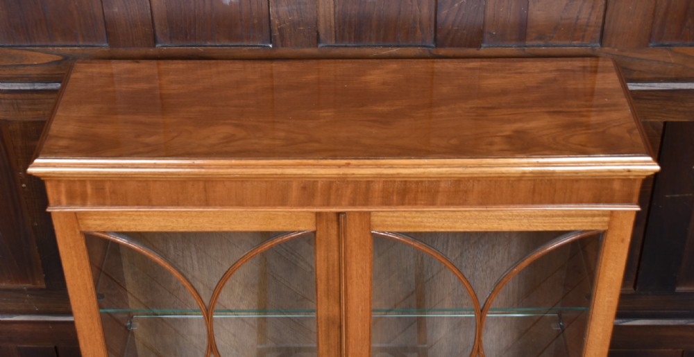An Edwardian mahogany display cabinet featuring two astragal-glazed doors, glass interior shelving, and splay bracket feet. View XII