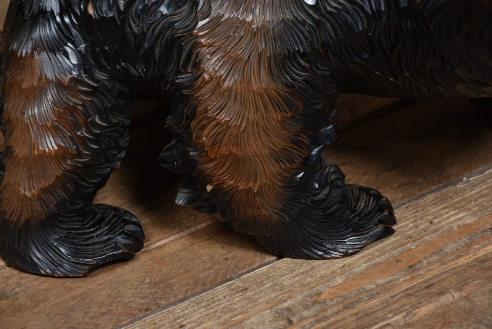 A hand-carved dark brown wooden bear sculpture depicted in a walking pose with an open jaw and chiselled fur detail. View V