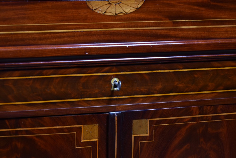 An antique Georgian mahogany writing desk with satinwood oval patera inlays, geometric stringing, two cupboard doors, and a hinged lid. View III