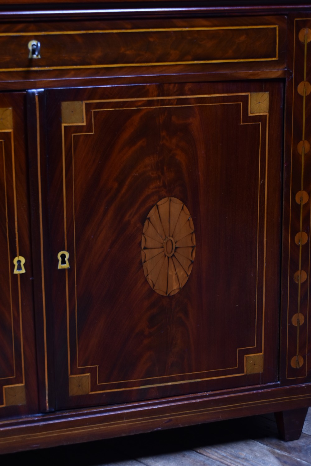 An antique Georgian mahogany writing desk with satinwood oval patera inlays, geometric stringing, two cupboard doors, and a hinged lid. View V