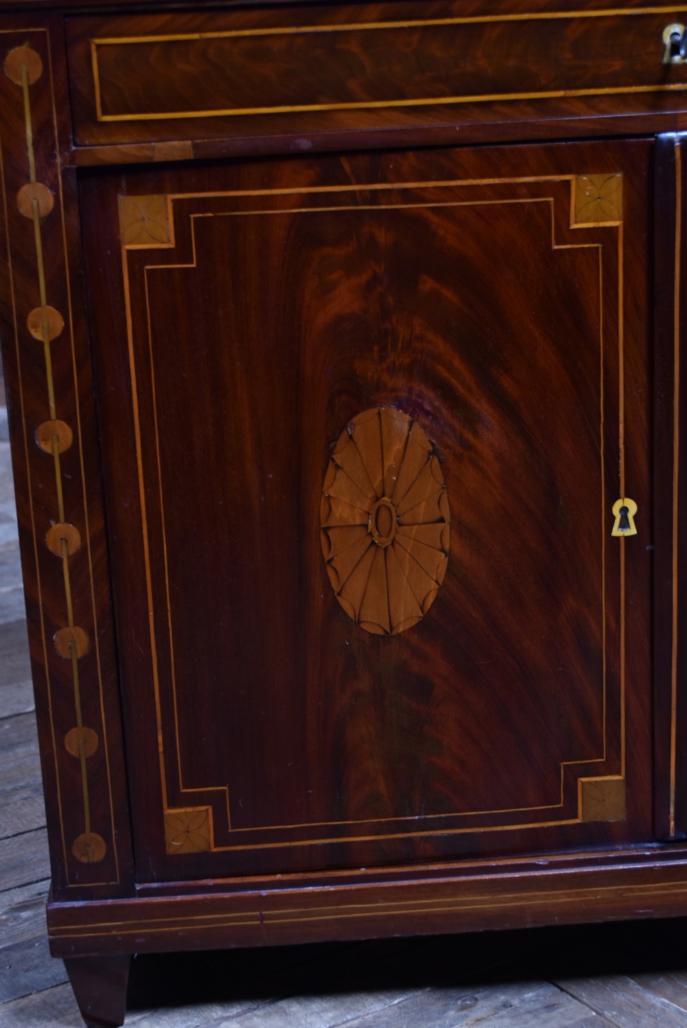 An antique Georgian mahogany writing desk with satinwood oval patera inlays, geometric stringing, two cupboard doors, and a hinged lid. View VI