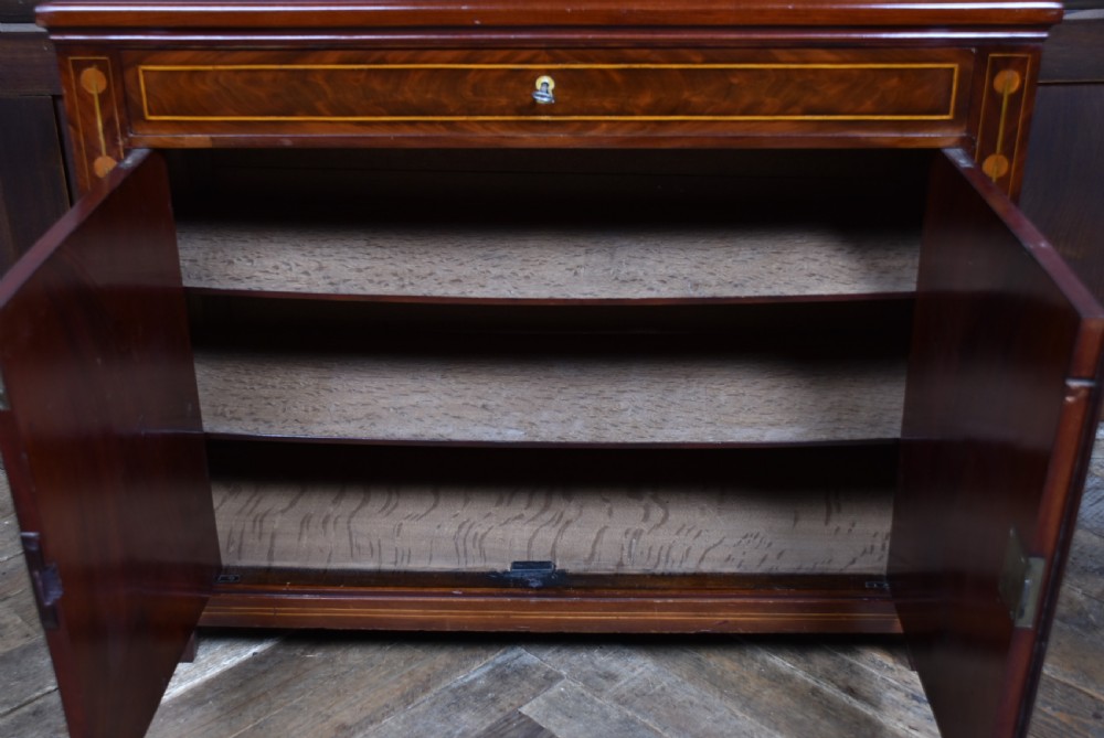 An antique Georgian mahogany writing desk with satinwood oval patera inlays, geometric stringing, two cupboard doors, and a hinged lid. View IX