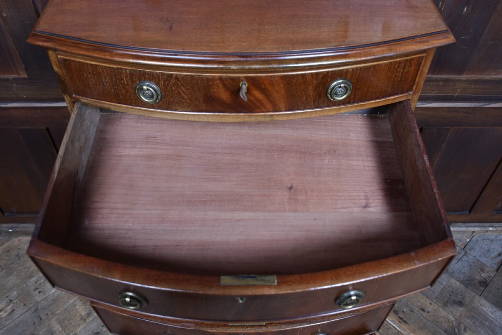 An Edwardian mahogany bow-front chest of drawers featuring six graduating drawers with brass ring handles and splayed bracket feet. View VIII