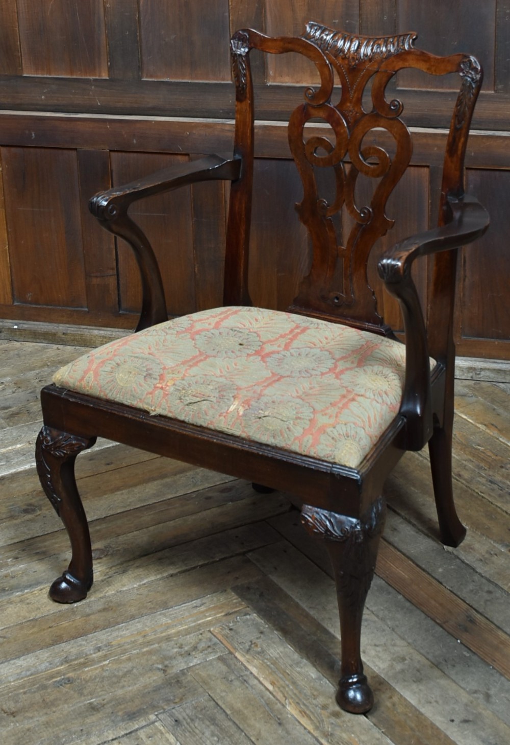 A Georgian mahogany open armchair featuring a pierced carved back splat, out-swept arms, patterned upholstery, and cabriole front legs.