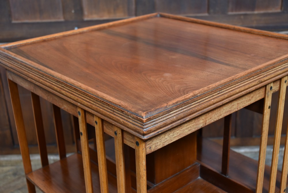 An Edwardian square walnut revolving bookcase featuring two tiers with vertical slatted sides and a flat moulded top surface. View III