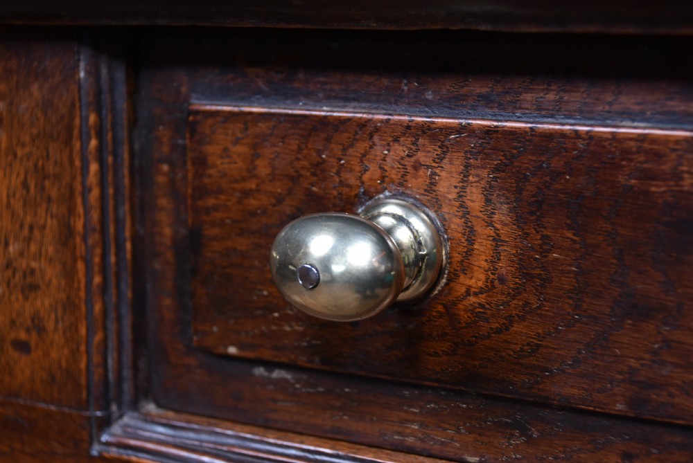A 19th-century dark oak French provincial dresser featuring an open upper plate rack with a scalloped top apron over three drawers and two panelled cupboard doors. View VIII