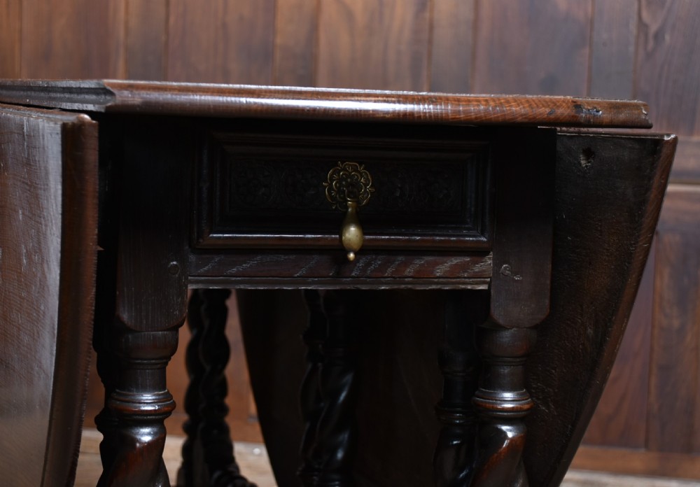 An 18th-century dark oak drop-leaf table featuring barley-twist turned legs, stretchers, and hinged folding side panels. View V