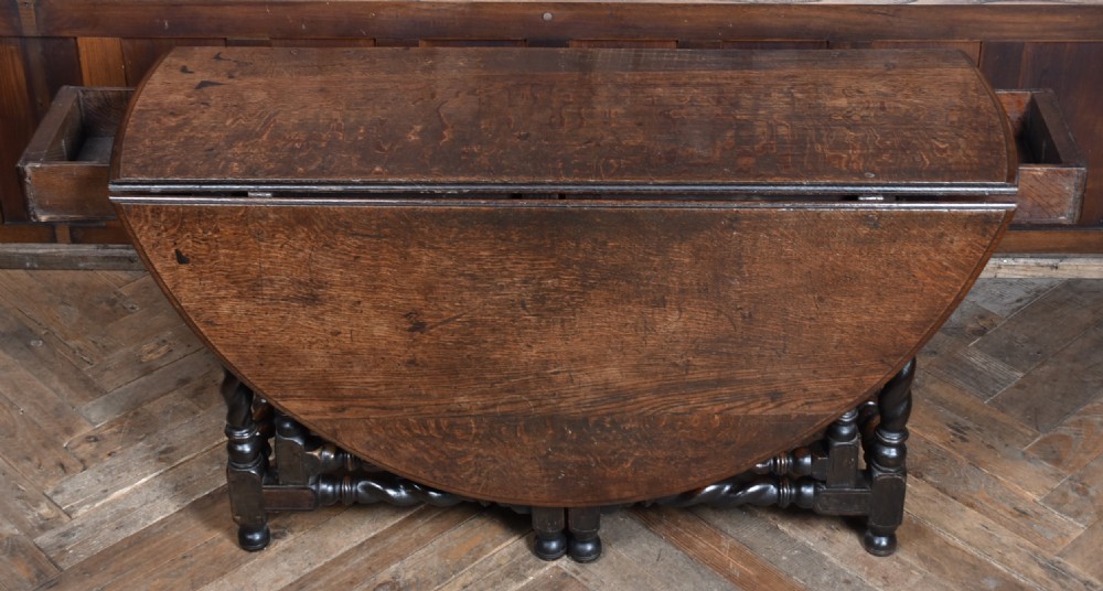 An 18th-century dark oak drop-leaf table featuring barley-twist turned legs, stretchers, and hinged folding side panels. View X
