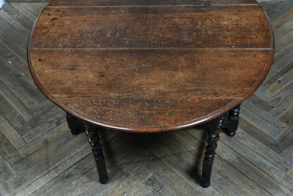 An 18th-century dark oak drop-leaf table featuring barley-twist turned legs, stretchers, and hinged folding side panels. View XIII