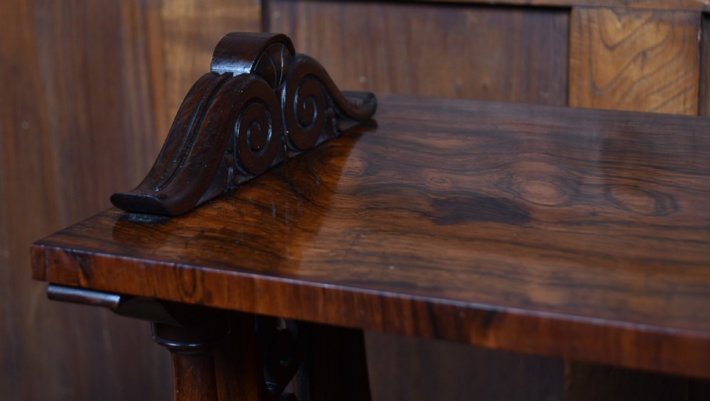 A three-tiered Victorian rosewood whatnot shelf featuring turned support columns, carved top details, and a single lower drawer with twin circular knobs. View VII