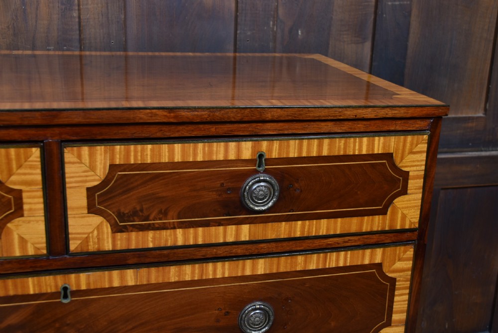 A Georgian mahogany chest of drawers featuring two short over two long drawers with intricate inlaid borders and splayed bracket feet. View VI