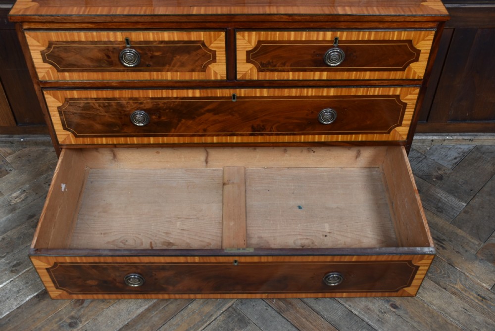 A Georgian mahogany chest of drawers featuring two short over two long drawers with intricate inlaid borders and splayed bracket feet. View X