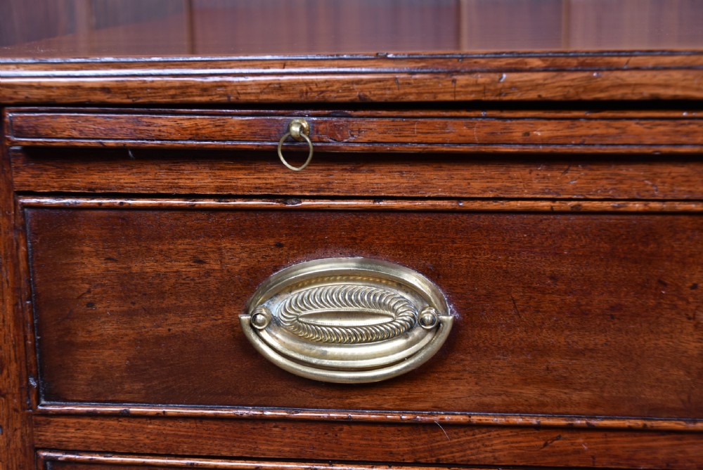 A Georgian mahogany bachelor chest featuring four graduated drawers with brass oval handles, a pull-out brushing slide, and bracket feet. View IV