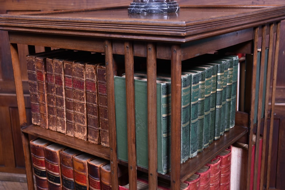 An Edwardian warm brown walnut three-tier revolving bookcase with vertical slatted sides resting on castors. View II