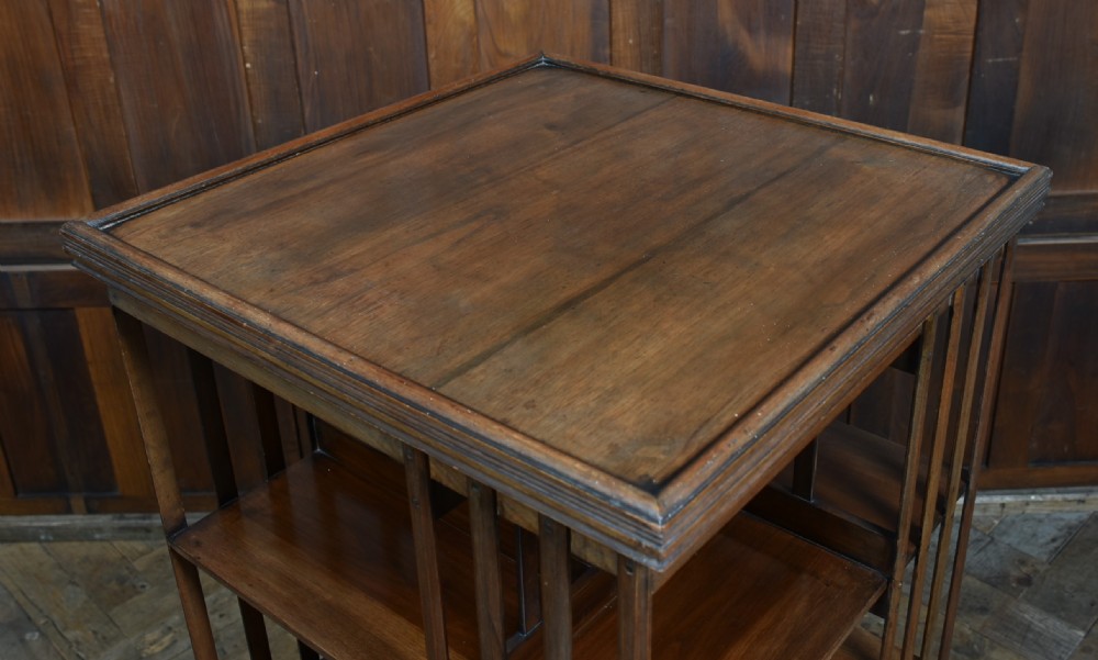 An Edwardian warm brown walnut three-tier revolving bookcase with vertical slatted sides resting on castors. View IV