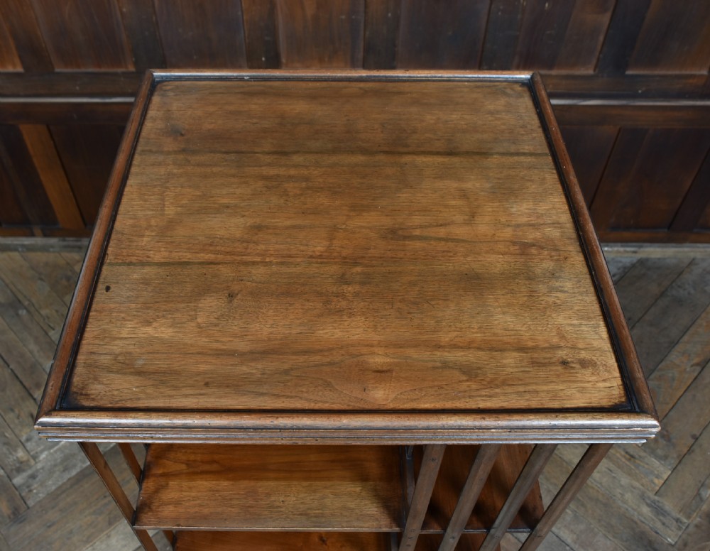 An Edwardian warm brown walnut three-tier revolving bookcase with vertical slatted sides resting on castors. View IX